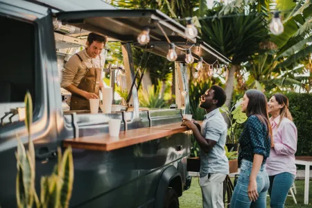 Three people ordering drinks from a food truck