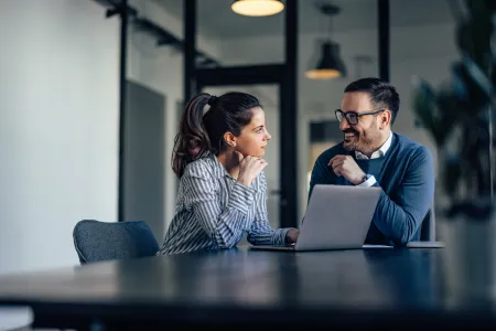 Woman and man talking behind computer at conference table