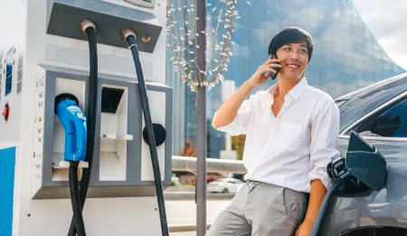 Man talking on phone at EV charging station