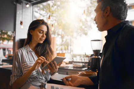 Woman using tablet to ring up customer at coffee shop