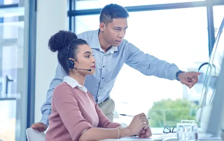 Shot of a young businessman assisting a colleague in a call centre.png