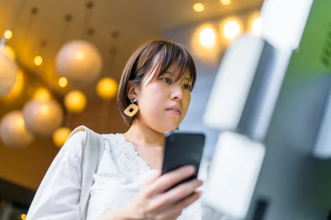 Woman using phone for payment at kiosk